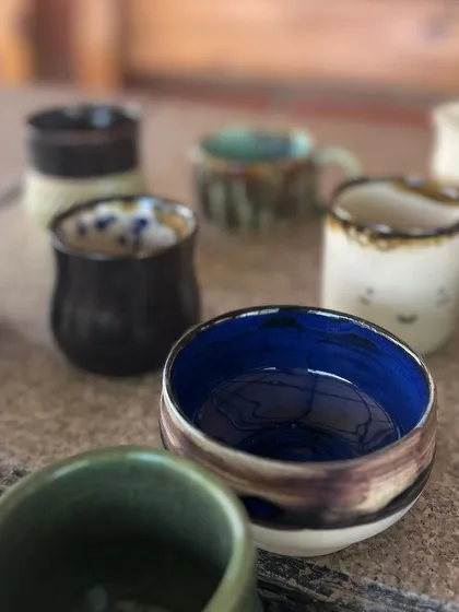 A collection of finished pots from my beginner wheel throwing course. The variety of shapes and glazes is a testament to their hard work and creativity.