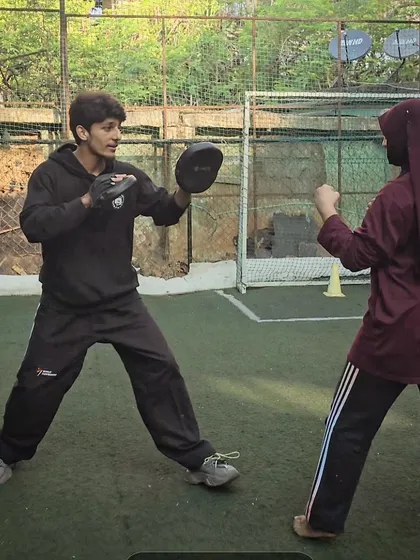 Personal attention is key even in group settings. Here, I'm working one-on-one with a student on her boxing technique using focus mitts during a class in Fraser Town.