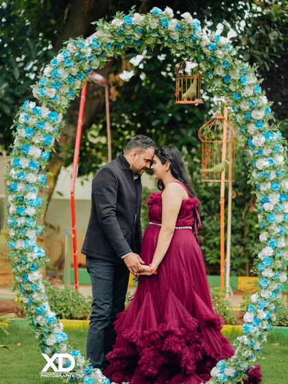 An intimate moment captured as a couple touches foreheads inside a beautiful floral arch.