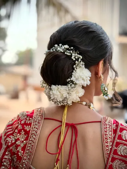 A close-up of the classic bridal bun, adorned with fresh baby's breath and white carnations. This hairstyle is both elegant and timeless.