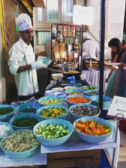 My chef is ready to prepare customized dishes at a live station, with a wide array of fresh, chopped ingredients. This setup is perfect for interactive food experiences like a build your own bowl concept.
