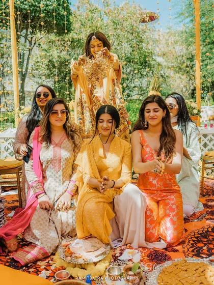 The bride performs the Kaleerey ceremony for her bridesmaids, who are seated and eagerly waiting.