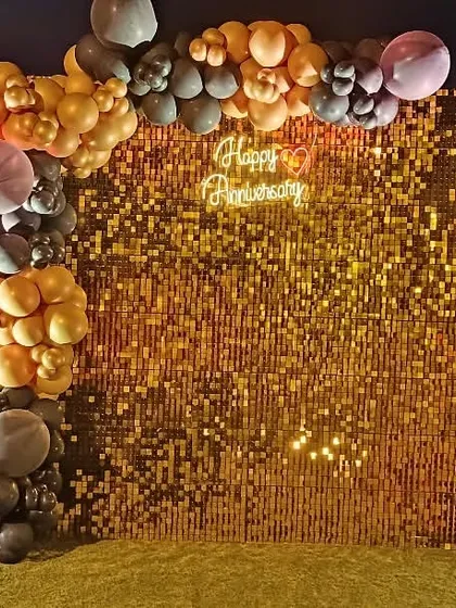 An anniversary party backdrop with a gold sequin panel, a 'Happy Anniversary' neon sign, and custom side panels reading 'Better Together' and 'Cheers to Celebration'.