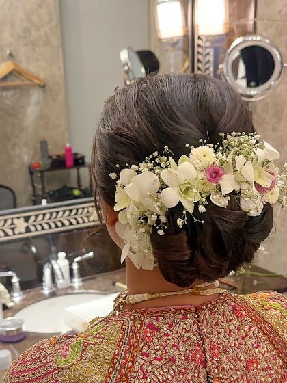An ethereal and romantic bridal bun, generously decorated with a mix of white orchids, baby's breath, and other delicate flowers.
