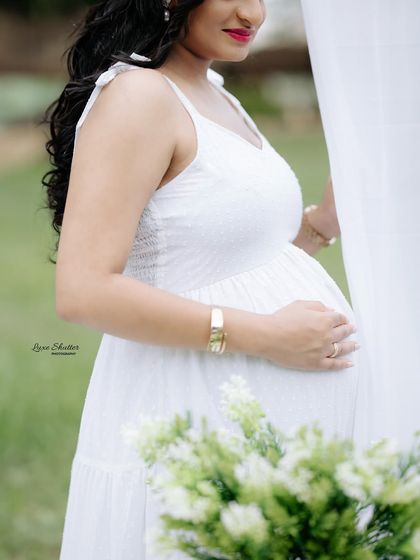 A simple, beautiful close-up of the mother-to-be cradling her bump. The soft, natural light of an outdoor setting is incredibly flattering and creates a gentle mood.