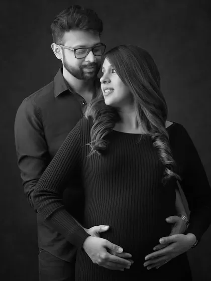 A full-length view of a couple's pose during a moody maternity session. The dark attire and background create a sophisticated and dramatic portrait.