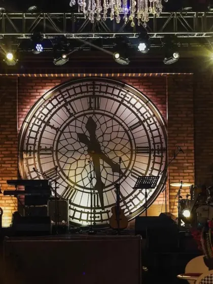 The stage is the heart of the party. For the speakeasy theme, we constructed a custom backdrop featuring a giant, backlit clock face against a rustic brick wall, creating a powerful focal point for the live band and performances.