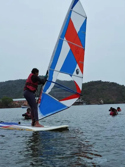 A participant carefully pulls up the sail, learning the first steps of windsurfing at our Karwar camp.