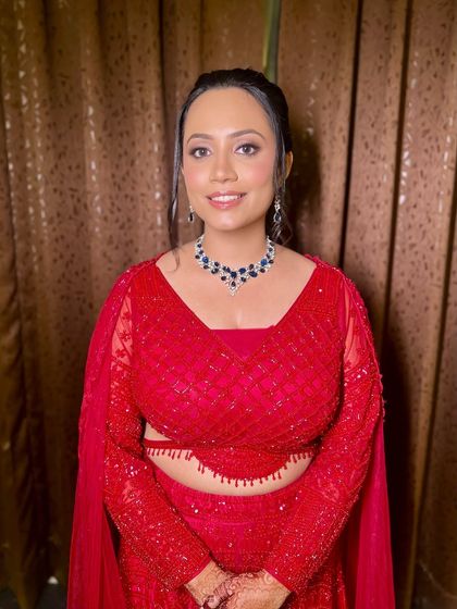 A full view of Archana's stunning red sangeet outfit, perfectly complemented by her fresh and dewy makeup.