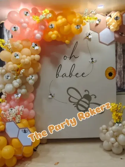 The full setup for the "Oh Babee" themed baby shower, with a custom backdrop, honeycomb props, and a beautiful balloon garland.
