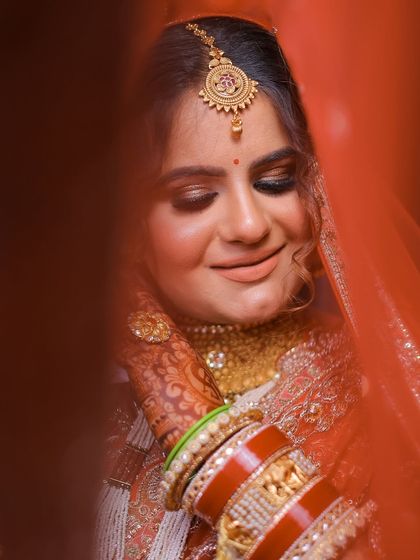 A shy, candid moment of the bride captured through her red veil. This is a classic shot that feels timeless.