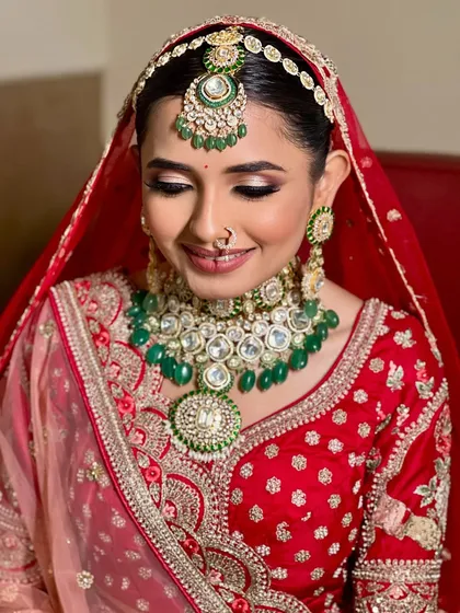 A serene portrait of the bride looking down, showcasing her soft glam makeup. The shimmer on her eyelids and the perfectly matched jewelry create a harmonious look.