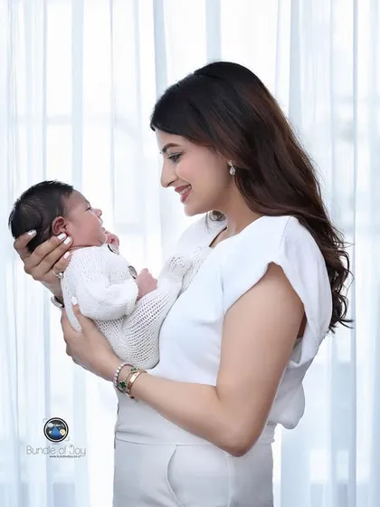 A candid moment between a mother and her newborn. The soft, natural light from the window creates a gentle and intimate feel, perfect for lifestyle newborn photography.