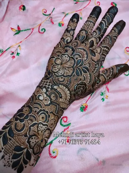 A close-up of a dense floral pattern, where flowers and leaves intertwine to create a rich tapestry of henna art on the arm.