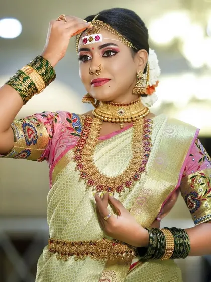 The bride adjusting her maang tikka, giving a clear view of the headpiece and earrings.