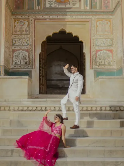 A fun and playful pose on the steps of the Ganesh Pol. This shot captures the couple's joyful personalities against one of Jaipur's most iconic and colorful backdrops.