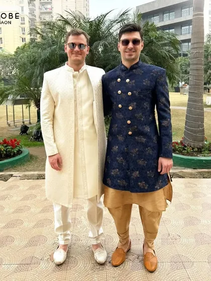 Here you can see two different styles side-by-side. One gentleman wears a classic cream sherwani while the other sports a navy blue printed Indo-western jacket, showing the variety I offer.