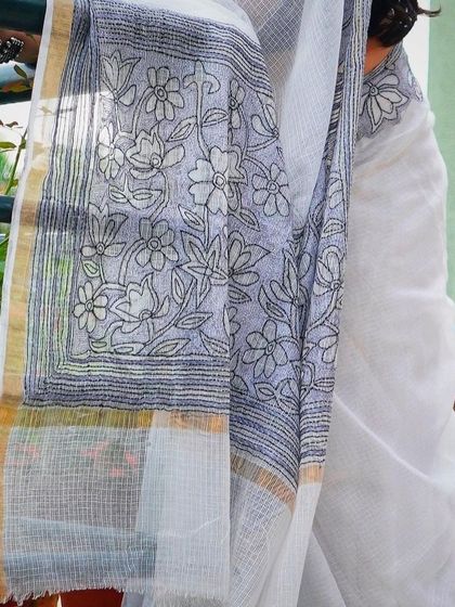 A close-up of the intricate pallu of a contemporary white saree with black floral embroidery.