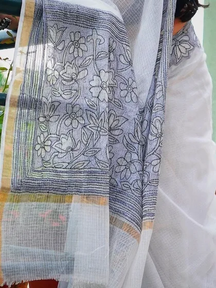 A close-up of the intricate pallu of a contemporary white saree with black floral embroidery.