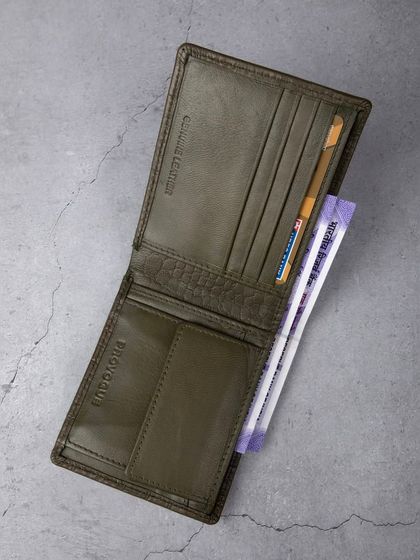 An open view of the green crocodile wallet, showing its interior layout with cards and cash.