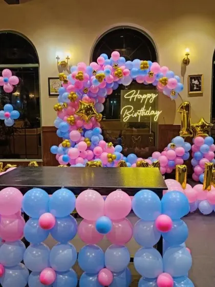 A gender-neutral or twins' birthday party with a pink and blue theme. The moon-shaped balloon arch and table base are split into two colors, creating a fun and balanced look.
