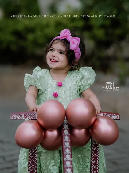 Capturing the pure, unfiltered joy of childhood is what we love most. This outdoor portrait for Bhoomija's first birthday shoot shows her delightful personality shining through as she plays with her little walker.
