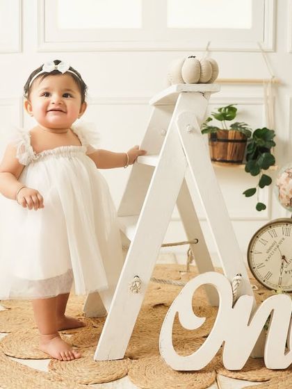 Standing proudly in her beautiful white dress, this one-year-old is the star of her classic and timeless birthday portrait session.