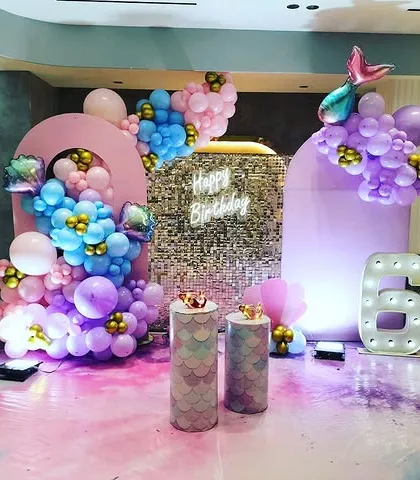 A glamorous take on the Mermaid theme with a silver shimmer wall, marquee number '6', and a pastel balloon arrangement with mermaid tail accents.