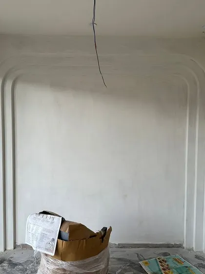 Before: The initial state of a bedroom wall in 'Project Lily', prepped for custom paneling and finishing.