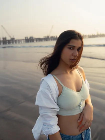 A raw, unedited feel. This portrait, taken as the sun sets, focuses on a natural expression with the sea and a distant coastal project in the background.