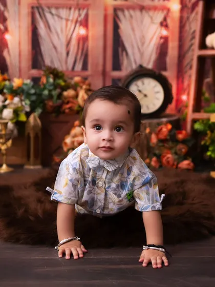 A handsome little boy crawling on a rustic set. The warm wood tones and soft lighting create a timeless and classic portrait.
