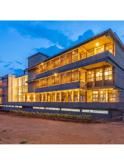 The RSL Office building in Bengaluru at twilight. The facade features parametric terracotta jaali screens that glow from within, showcasing how sustainable design can also be architecturally striking.
