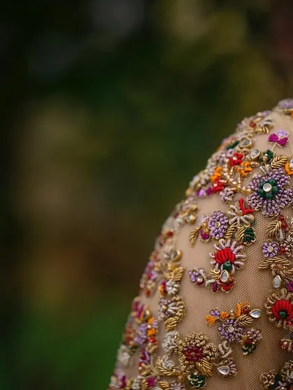 This is where the magic lies. A close up of a hand embroidered blouse sleeve, showcasing intricate, multi colored floral zardozi and beadwork on sheer fabric. Each stitch is a testament to the hours of artistry poured into my creations.
