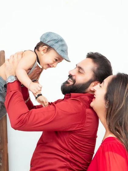 A playful family portrait, with dad lifting the baby high. We love capturing these joyful, energetic moments.