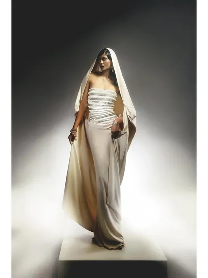 An elegant, hooded white gown from Rudraksh Dwivedi. The styling is minimalist and statuesque, creating a look of modern divinity.
