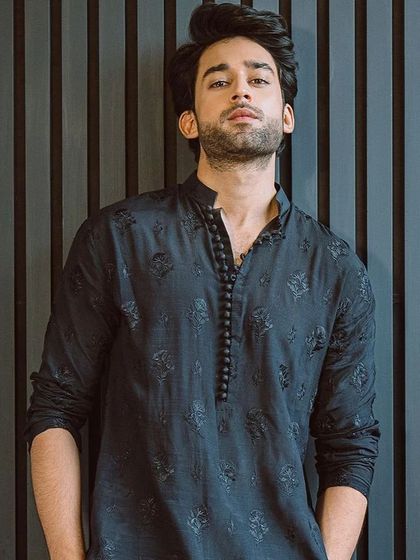 A simple yet elegant black kurta with self-design embroidery and a buttoned placket. This is a versatile piece that can be dressed up or down for any festive occasion.