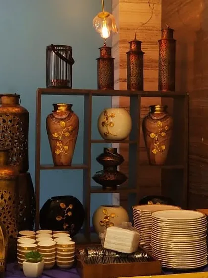 An elaborate decor shelf used as part of a festive buffet. The antique finish lanterns and vases create a rich, traditional ambiance perfect for Indian festivals and weddings.