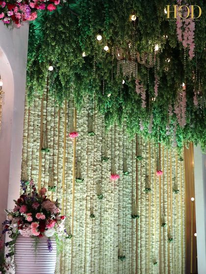 A ceiling of hanging greenery and flowers over a stage, creating a lush, garden-like canopy indoors.