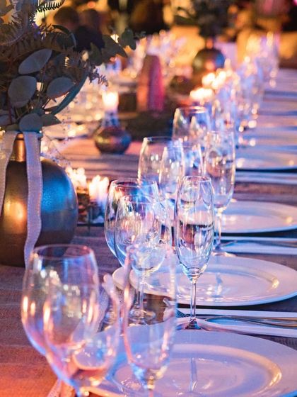 An elegant table setting for a reception dinner. The warm candlelight and clean glassware create a sophisticated and intimate ambiance for the guests.