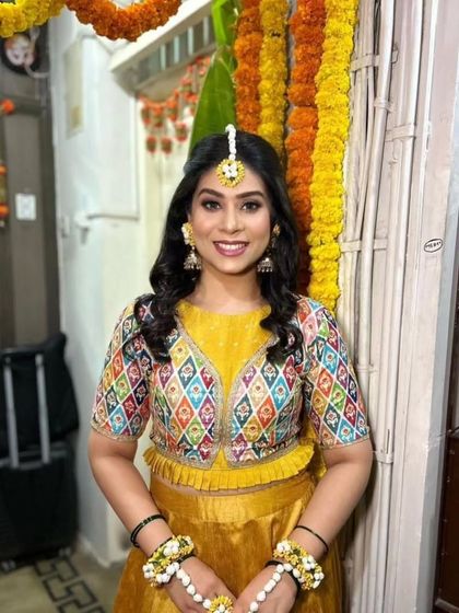 A happy portrait of the bride showing off her butterfly hairstyle and colorful Haldi outfit.