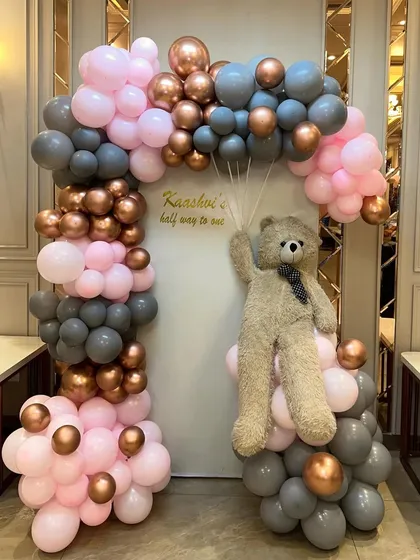 A full view of our popular teddy bear and balloon arch backdrop, designed in a lovely pink, grey, and rose gold color scheme for a half-birthday party.