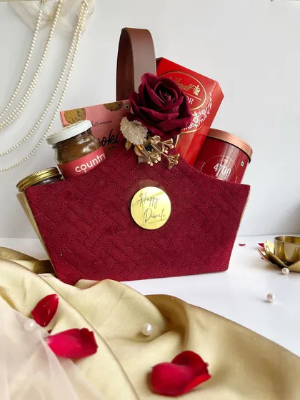 This rich maroon fabric basket is filled with gourmet goodies and adorned with a rose, making for a very elegant and traditional Diwali gift.