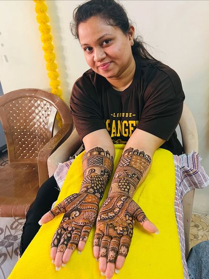 A close-up of a happy bride, pleased with her intricate and traditional mehndi design.