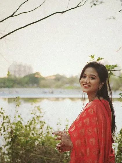 A happy portrait of a woman by a lake, with the cityscape in the background, blending nature and urban life.