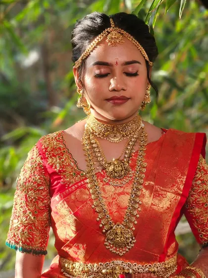 Archana's complete wedding look. The makeup is flawless, complementing her red Kanjivaram saree and traditional gold jewelry for a picture-perfect finish.