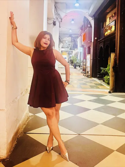 A more playful pose in the same birthday dress, leaning against a wall to show the dress's movement and fit.