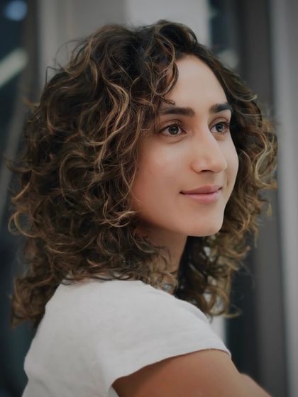 Fluffing up those curls like a pro. This medium-length curly cut is all about embracing volume and texture.