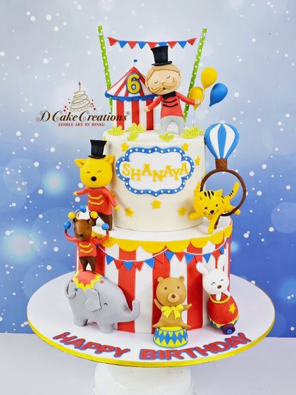 Step right up to this amazing two-tier circus cake for Shanaya's 6th birthday. It's full of fun, with a ringmaster, acrobatic animals, and a classic red-and-white striped tent.
