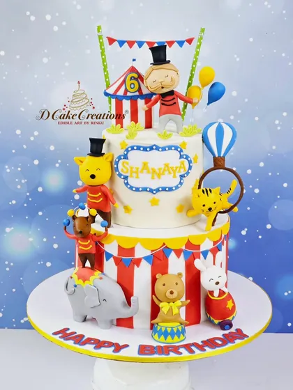 Step right up to this amazing two-tier circus cake for Shanaya's 6th birthday. It's full of fun, with a ringmaster, acrobatic animals, and a classic red-and-white striped tent.