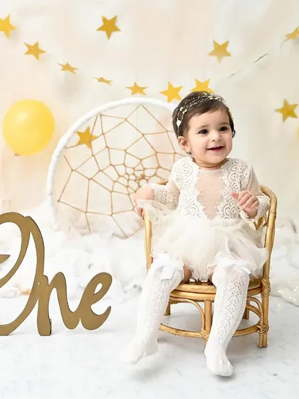 A star is one! This little girl shines brightly in a dreamy, celestial-themed setup with golden stars, fluffy clouds, and a beautiful dreamcatcher.